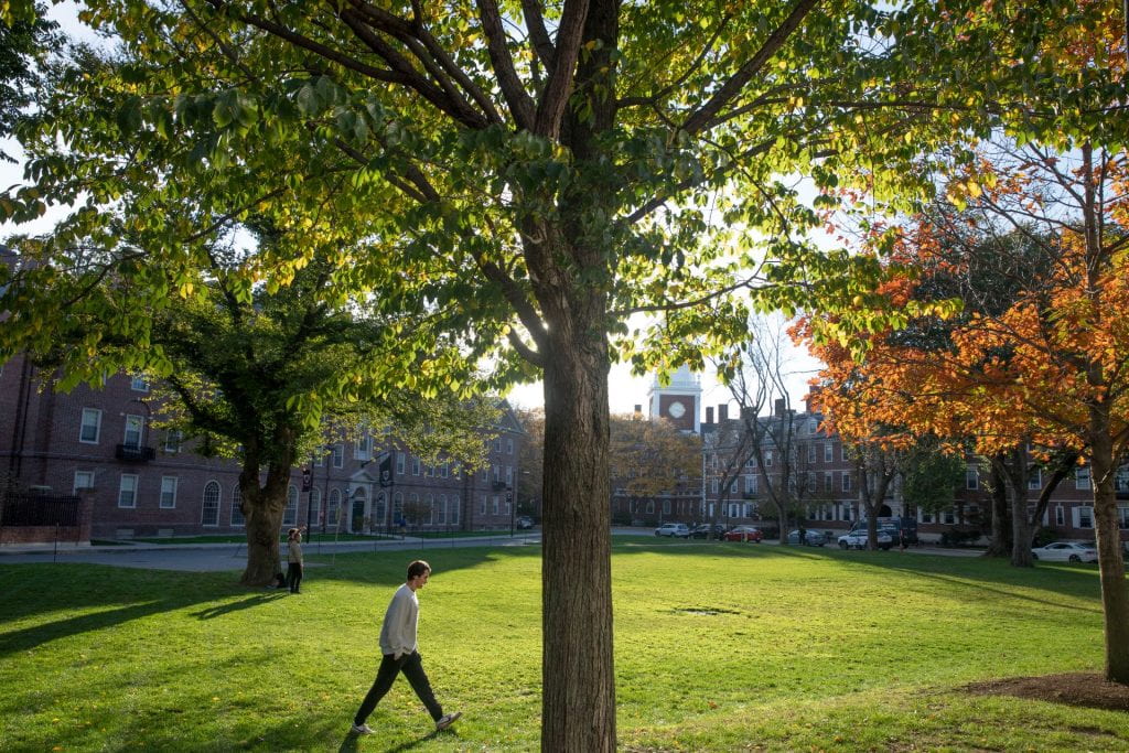 Student walking across the Harvard yard in the fall
